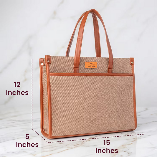 Brown tote bag with leather accents on a table with a coffee and pastry, set against an outdoor cafe background.