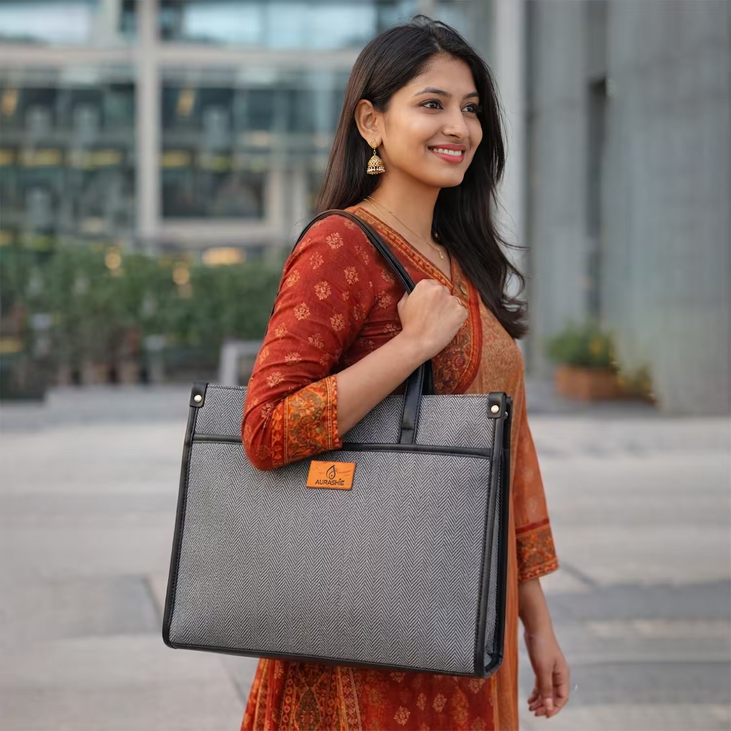 Woman holding a gray laptop bag outdoors with a blurred building background