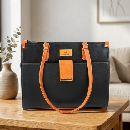 Black handbag with orange accents on a wooden table in a home setting