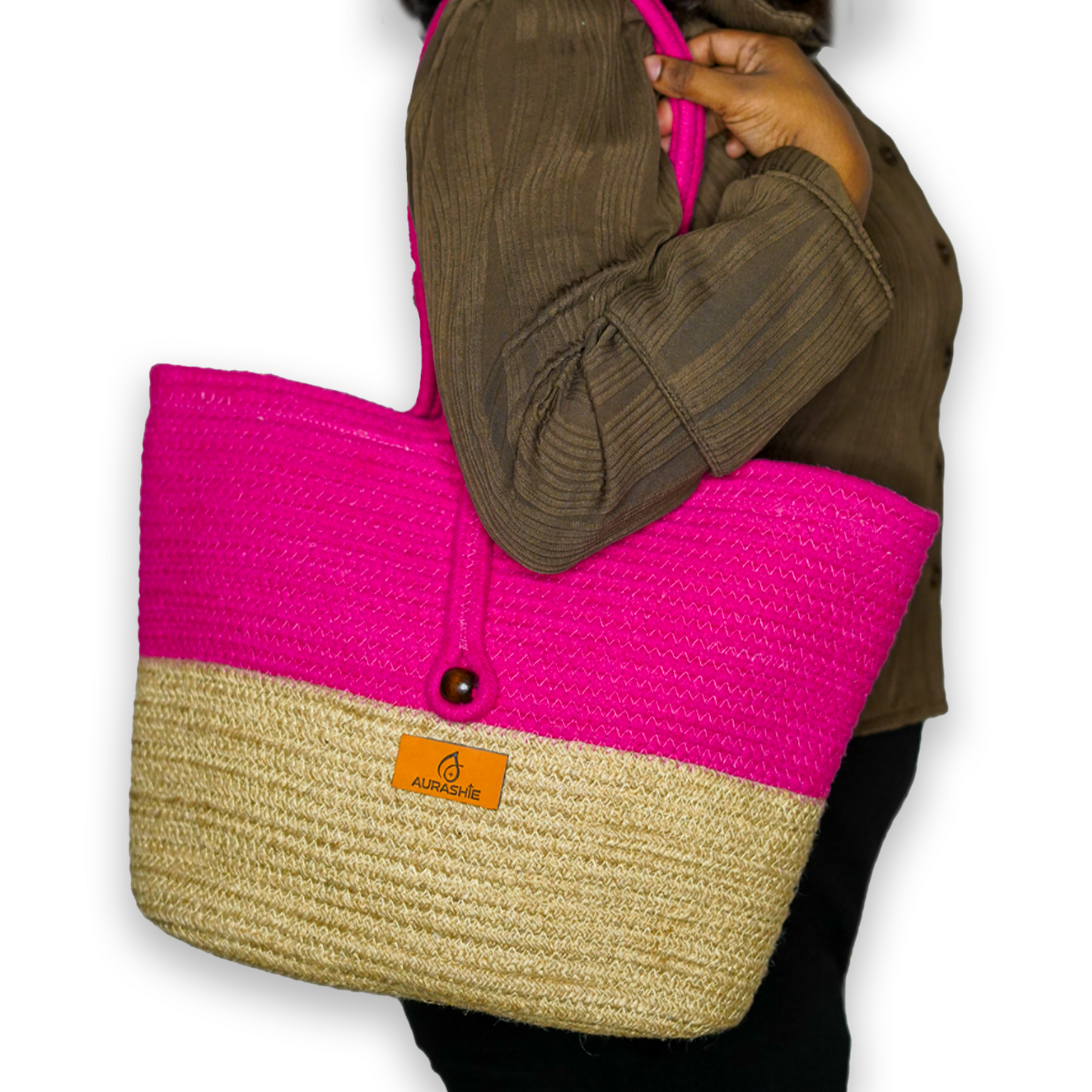 Person holding a pink and beige tote bag with a visible brand logo.