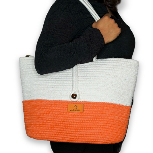 Person holding a white and orange tote bag with a visible brand logo.
