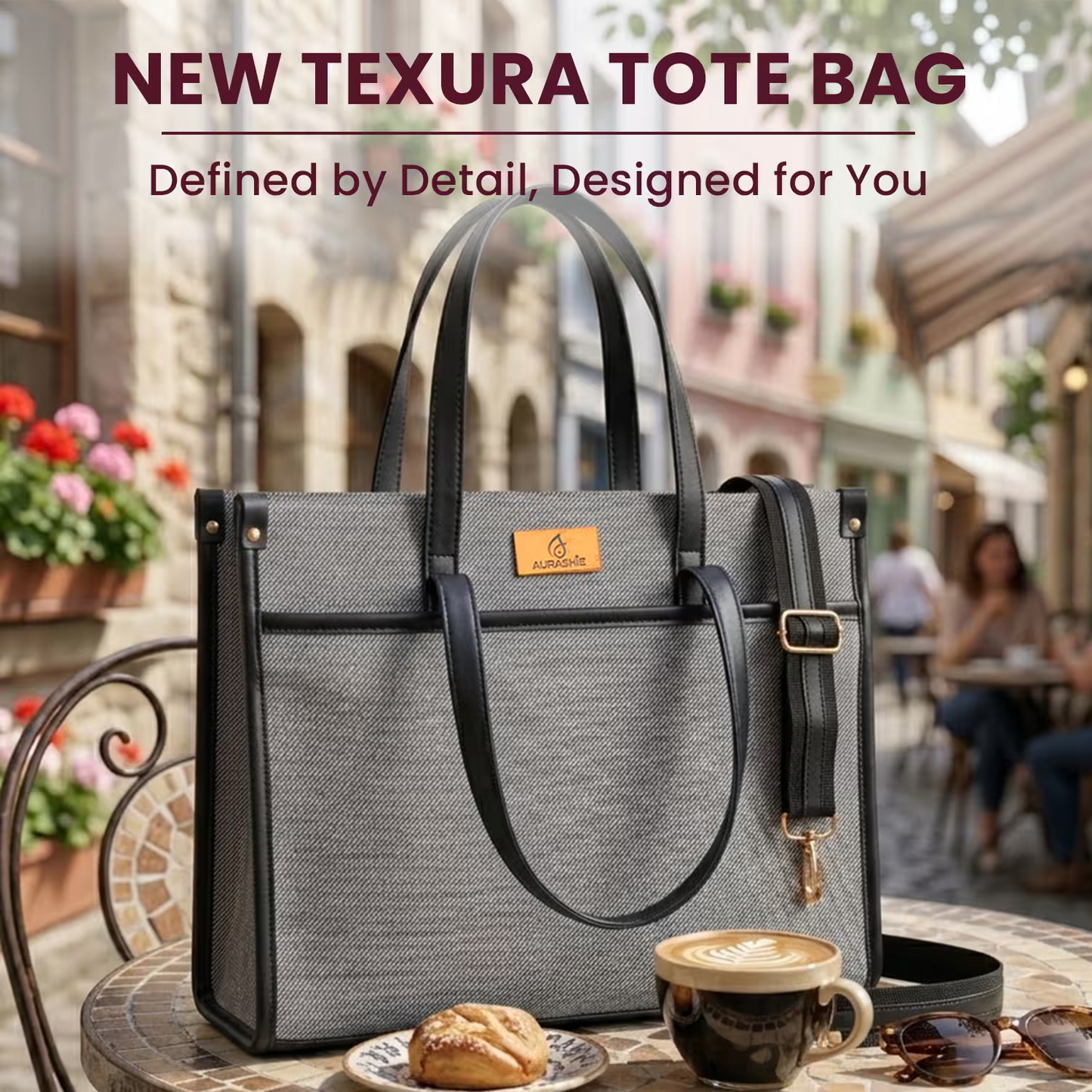 Gray tote bag with black handles on a table with a coffee cup and pastry, outdoor setting.