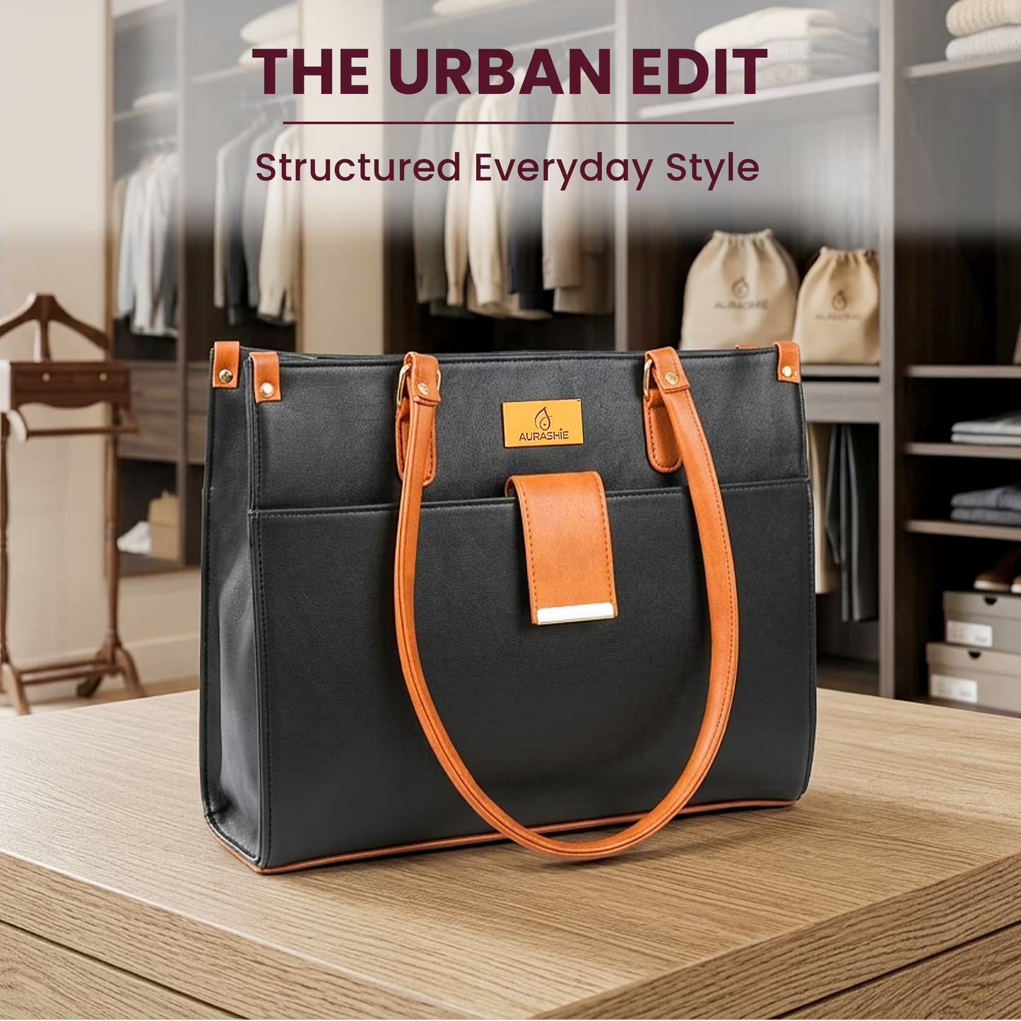 Black handbag with orange handles on a wooden surface, with 'The Urban Edit' branding.