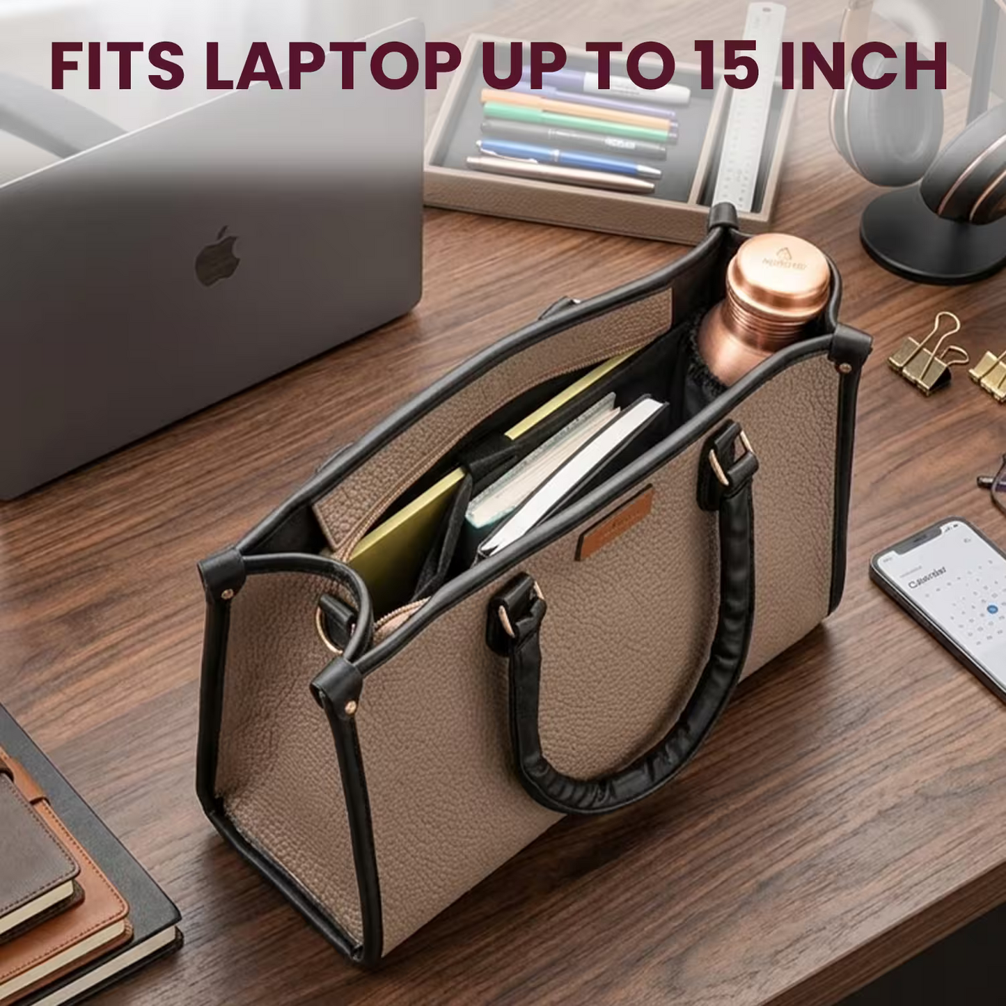 Beige handbag with black handles on a wooden desk containing a laptop, phone, and other items.
