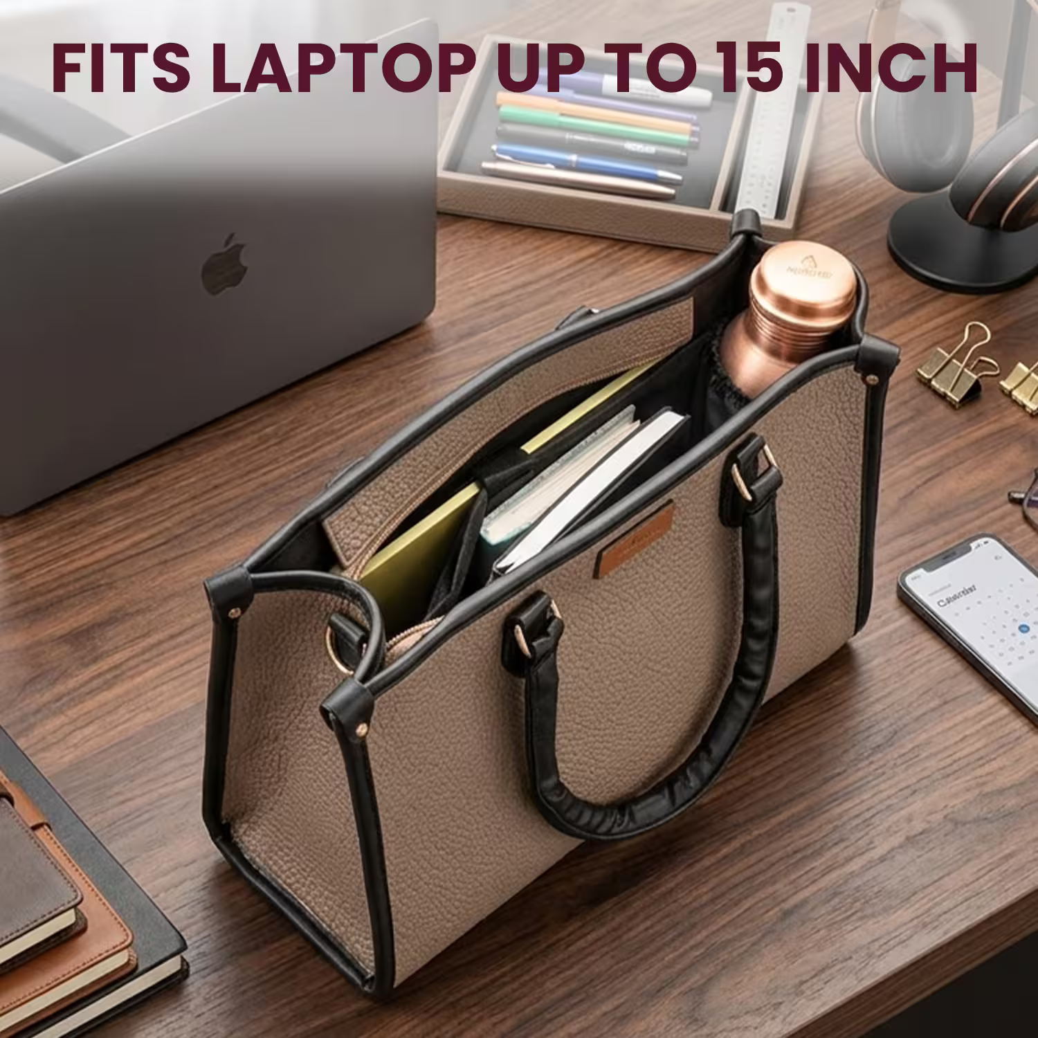 Beige handbag with black handles on a wooden desk containing a laptop, phone, and other items.