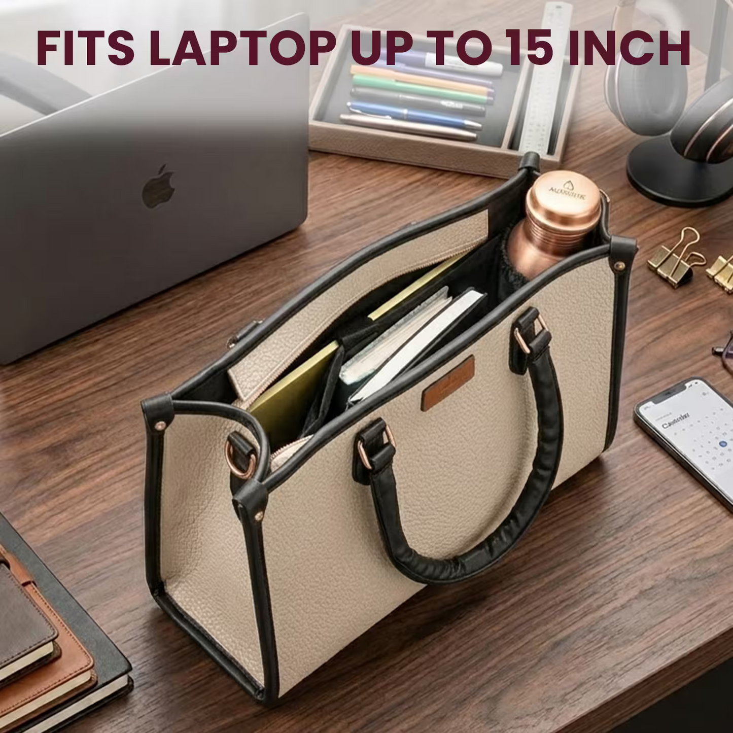 Beige handbag with black handles on a wooden desk with laptop and office supplies.