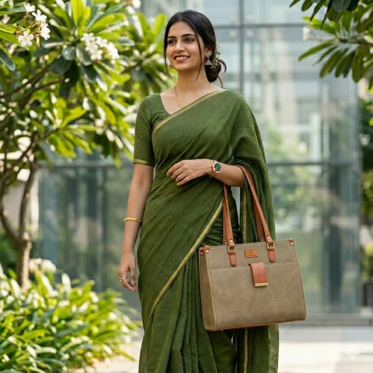 Woman in a green saree holding a beige handbag outdoors with greenery in the background