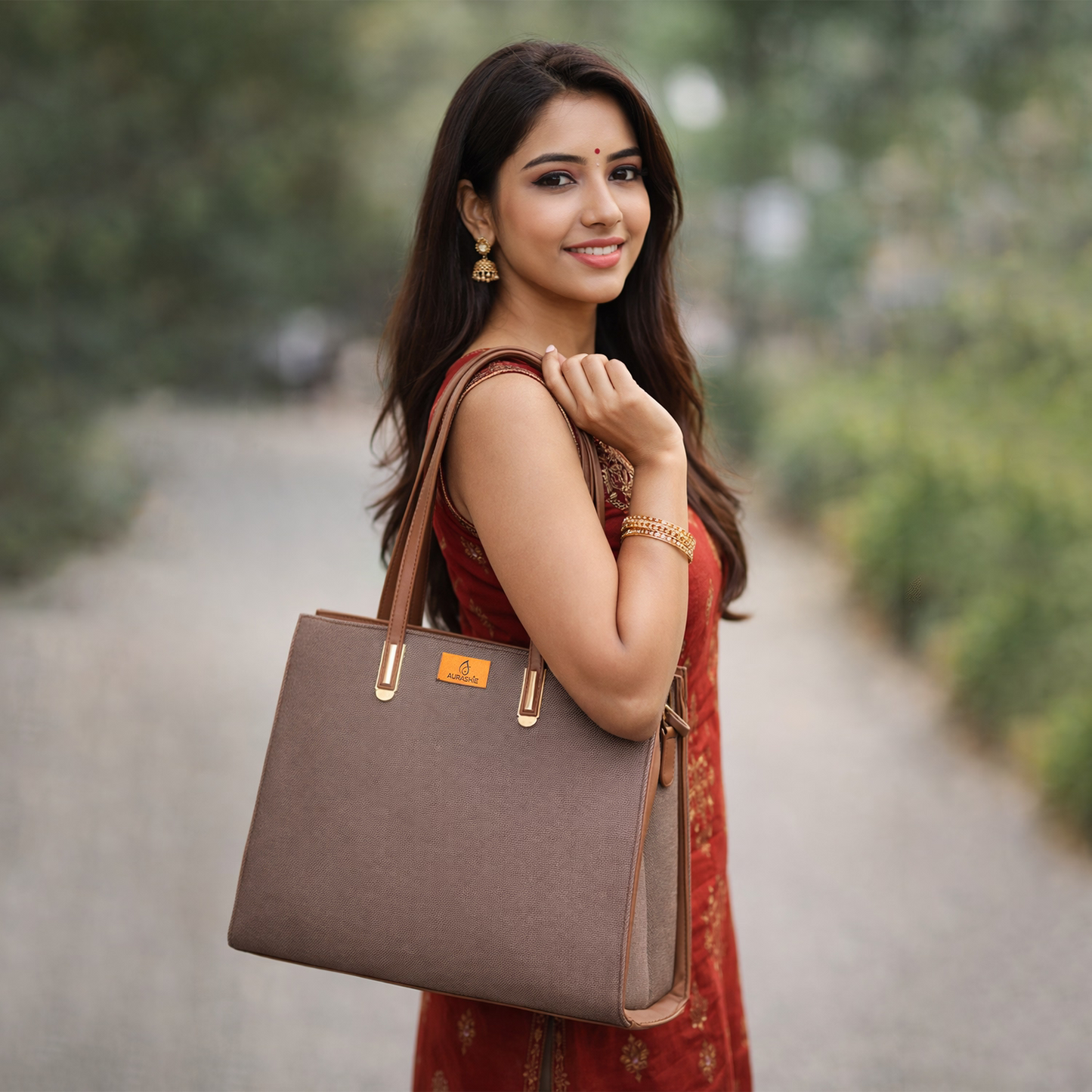 Woman holding a brown handbag outdoors with greenery in the background