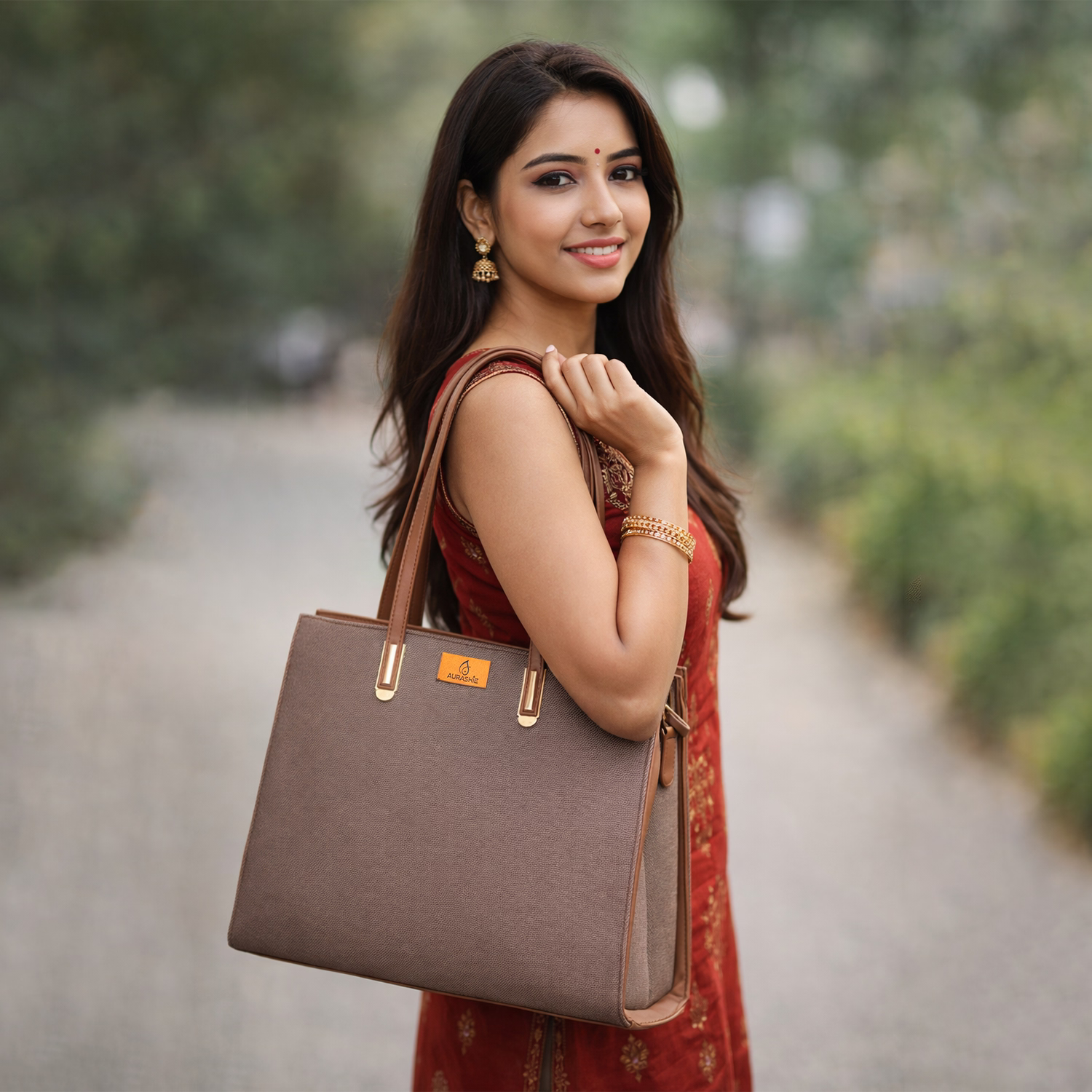Woman holding a brown handbag outdoors with greenery in the background