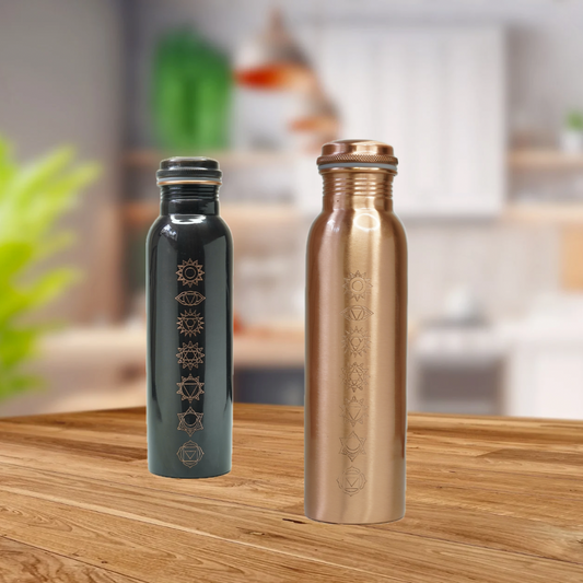 Two metallic water bottles, one black and one bronze, on a wooden surface with a blurred kitchen background.